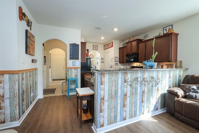 25106 Dickens Dr, Magnolia, TX 77355 - kitchen with black appliances, dark wood-type flooring, arched walkways, recessed lighting, and dark brown cabinetry