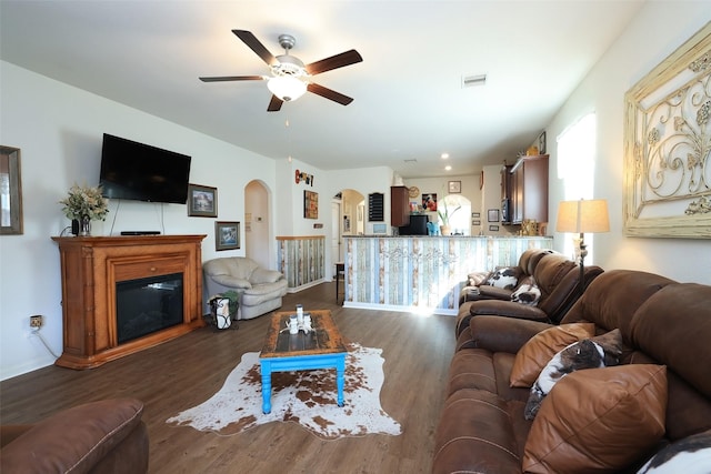 25106 Dickens Dr, Magnolia, TX 77355 - living area with arched walkways, wood finished floors, a ceiling fan, and a glass covered fireplace