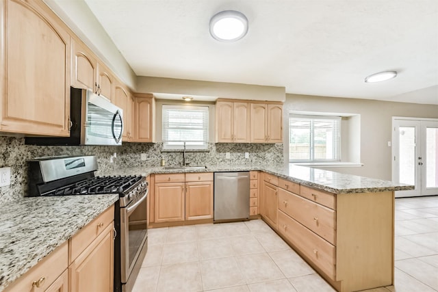 3313 Park Dale Dr, Deer Park, TX 77536 - kitchen with appliances with stainless steel finishes, light brown cabinetry, a peninsula, light stone counters, and decorative backsplash