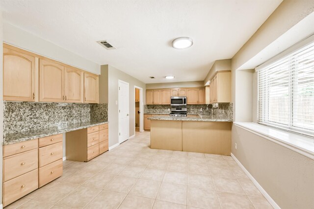 3313 Park Dale Dr, Deer Park, TX 77536 - kitchen with light brown cabinetry, appliances with stainless steel finishes, backsplash, built in desk, and light stone counters