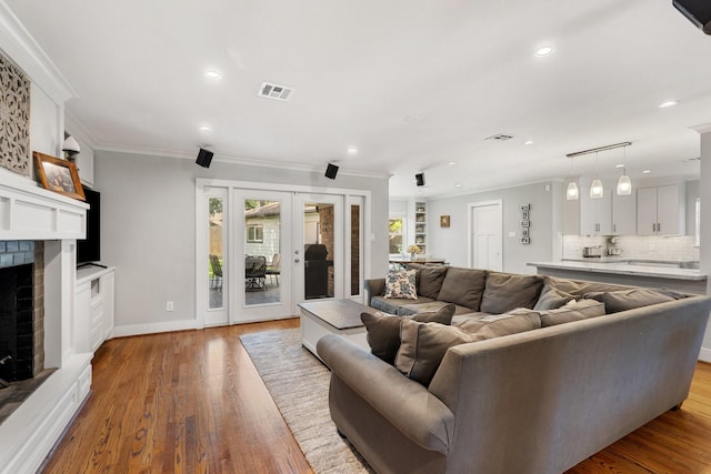 1011 Martin St, Houston, TX 77018 - living room featuring french doors, wood finished floors, crown molding, a brick fireplace, and recessed lighting