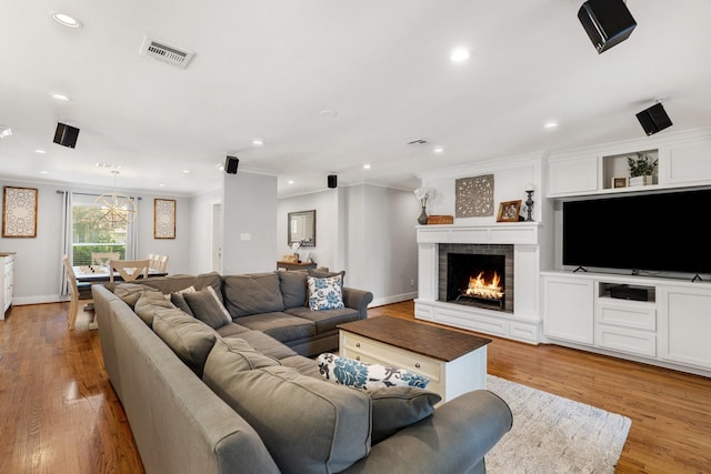 1011 Martin St, Houston, TX 77018 - living area featuring light wood-style floors, recessed lighting, ornamental molding, a lit fireplace, and a chandelier