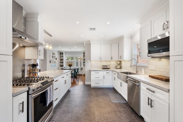 1011 Martin St, Houston, TX 77018 - kitchen featuring appliances with stainless steel finishes, wall chimney range hood, white cabinets, backsplash, and recessed lighting