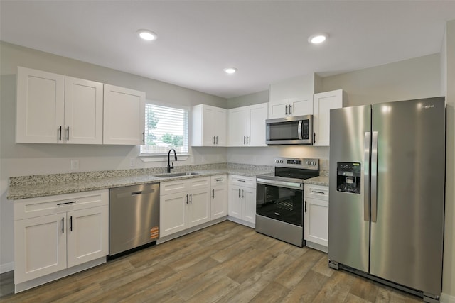 405 3rd St, Hempstead, TX 77445 - kitchen featuring appliances with stainless steel finishes, white cabinets, light stone counters, wood finished floors, and recessed lighting