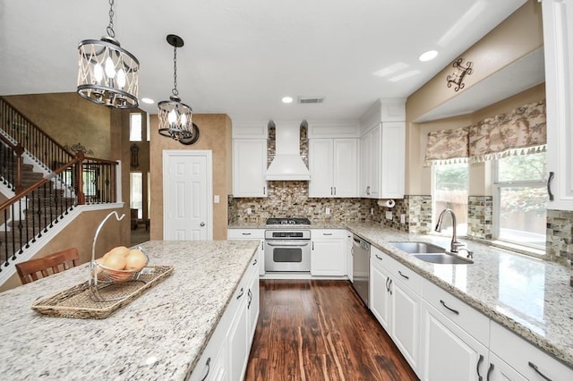 30103 Canyon Branch Ct, Spring, TX 77386 - kitchen with custom exhaust hood, stainless steel appliances, a chandelier, dark wood finished floors, and white cabinetry