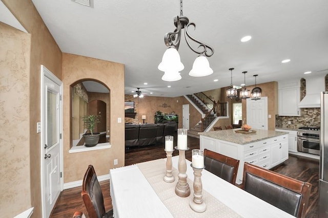 30103 Canyon Branch Ct, Spring, TX 77386 - dining area featuring a chandelier, dark wood-style floors, ceiling fan, stairs, and arched walkways