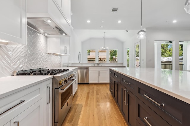 5216 Chestnut St, Bellaire, TX 77401 - kitchen featuring appliances with stainless steel finishes, white cabinets, light countertops, light wood-style floors, and tasteful backsplash