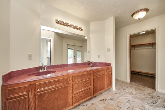 3515 Kansas St, Fresno, TX 77545 - bathroom with double vanity, french doors, marble finish floors, a textured ceiling, and a walk in closet