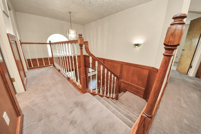 3515 Kansas St, Fresno, TX 77545 - staircase featuring a wainscoted wall, a textured ceiling, and a chandelier