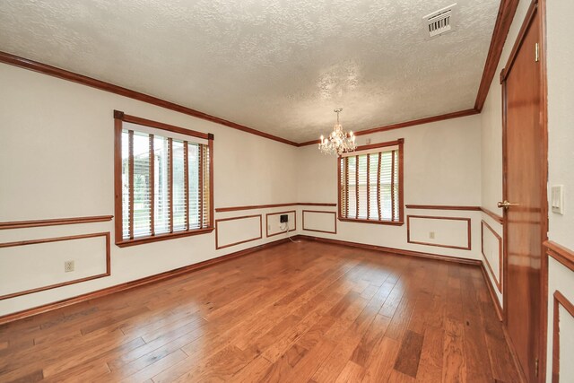 3515 Kansas St, Fresno, TX 77545 - empty room featuring a textured ceiling, a chandelier, hardwood / wood-style floors, a wainscoted wall, and ornamental molding
