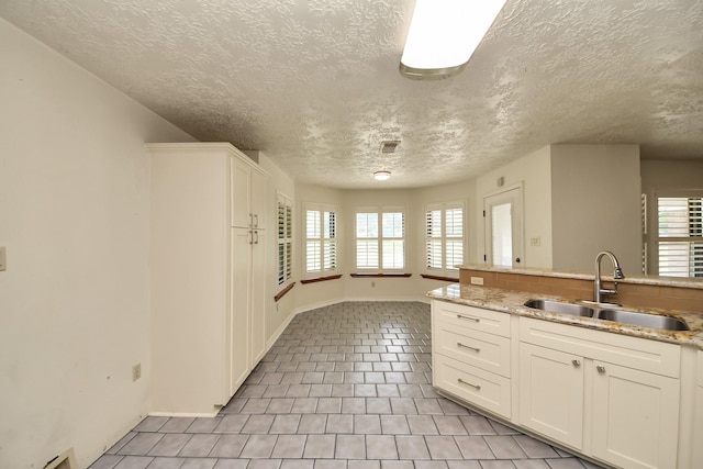 3515 Kansas St, Fresno, TX 77545 - kitchen with a textured ceiling, white cabinetry, light tile patterned floors, and light stone counters