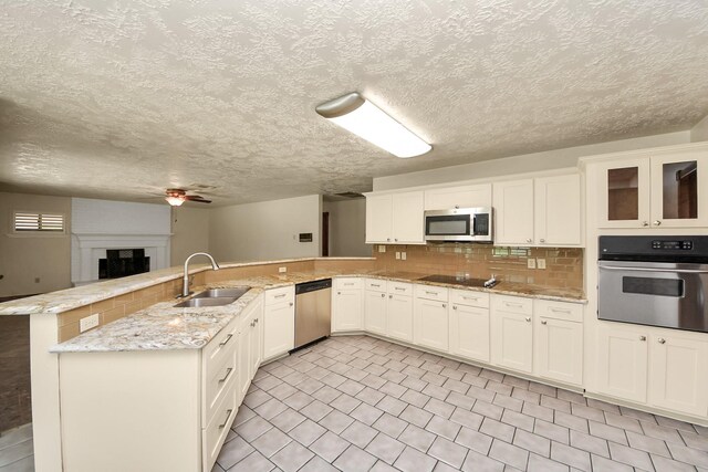 3515 Kansas St, Fresno, TX 77545 - kitchen with stainless steel appliances, a peninsula, ceiling fan, backsplash, and white cabinetry