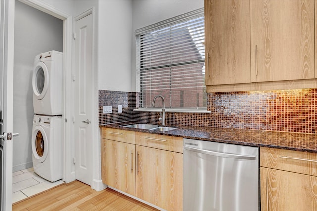2904 Chenevert St Unit J, Houston, TX 77004 - kitchen with stainless steel dishwasher, light brown cabinetry, stacked washer / drying machine, dark stone countertops, and decorative backsplash