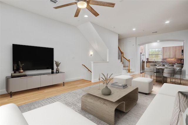 2904 Chenevert St Unit J, Houston, TX 77004 - living area featuring arched walkways, light wood finished floors, ceiling fan, recessed lighting, and stairs