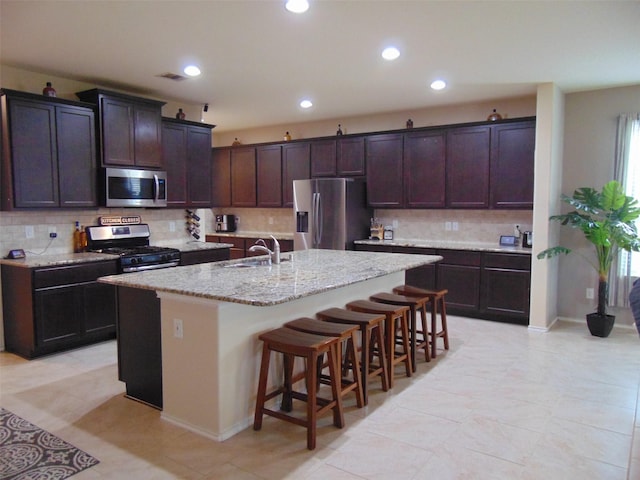 23727 Scotsman Dr, Katy, TX 77493 - kitchen with stainless steel appliances, a center island with sink, backsplash, recessed lighting, and a kitchen bar