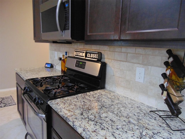 23727 Scotsman Dr, Katy, TX 77493 - kitchen with appliances with stainless steel finishes, decorative backsplash, dark brown cabinets, and light stone counters