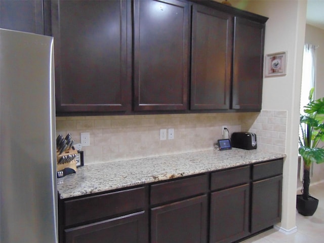 23727 Scotsman Dr, Katy, TX 77493 - kitchen with freestanding refrigerator, tasteful backsplash, dark brown cabinetry, and light stone counters