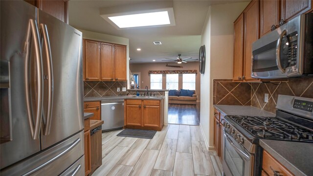 18527 Grove Brook Ln, Cypress, TX 77429 - kitchen featuring stainless steel appliances, a peninsula, decorative backsplash, brown cabinetry, and open floor plan