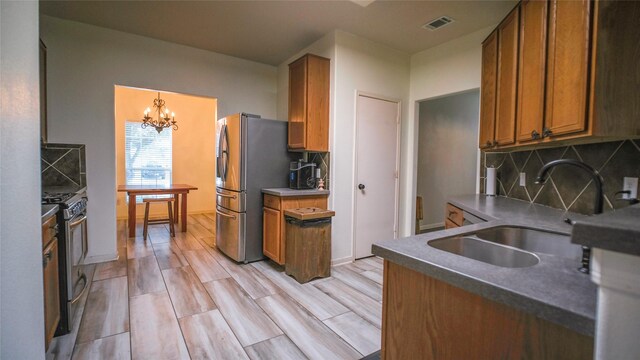 18527 Grove Brook Ln, Cypress, TX 77429 - kitchen with stainless steel appliances, backsplash, brown cabinets, and a chandelier