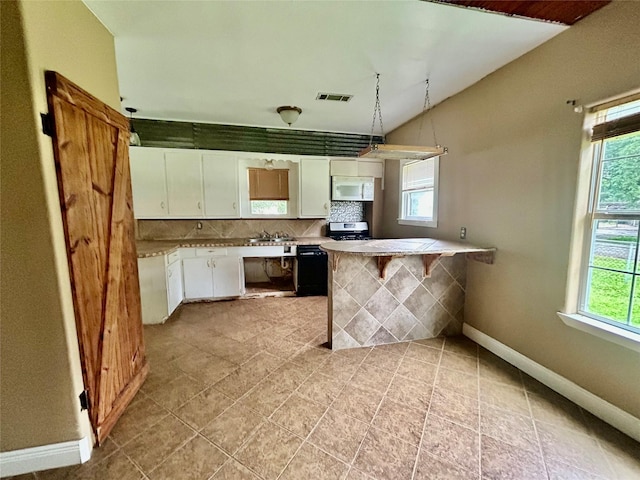 5119 33rd St, Groves, TX 77619 - kitchen featuring white microwave, white cabinets, a peninsula, lofted ceiling, and light countertops