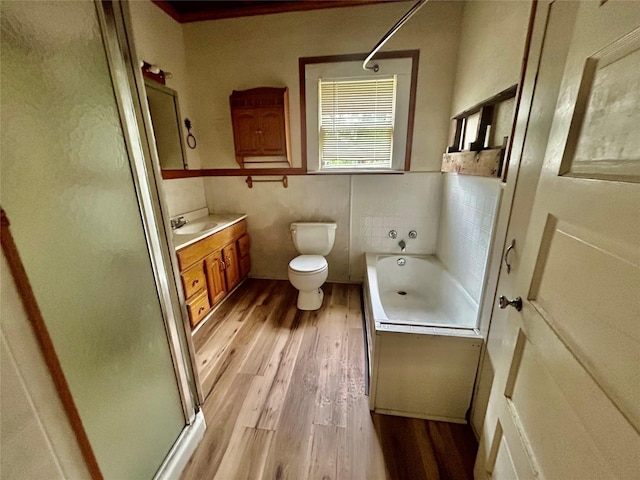 5119 33rd St, Groves, TX 77619 - bathroom featuring wood finished floors, a stall shower, vanity, a garden tub, and tile walls