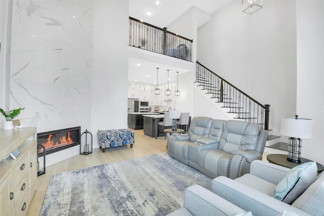 16634 Lake Austin St, Cypress, TX 77433 - living room featuring light wood finished floors, a high ceiling, a fireplace, stairway, and recessed lighting