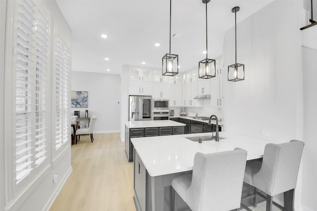 16634 Lake Austin St, Cypress, TX 77433 - kitchen featuring appliances with stainless steel finishes, light wood finished floors, light countertops, white cabinets, and a center island