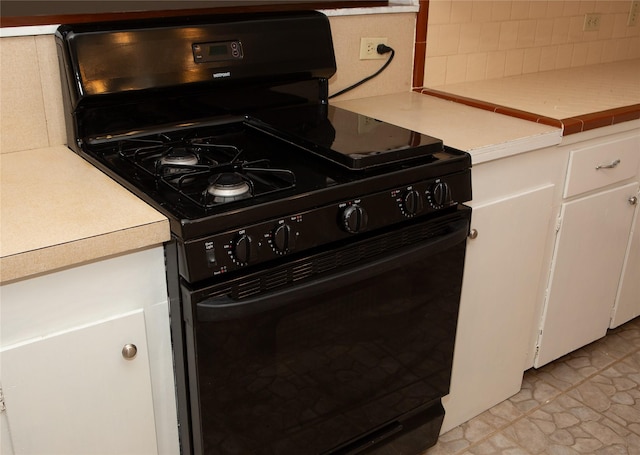 6718 E Bayou Dr, Hitchcock, TX 77563 - kitchen view of black stove, decorative backsplash, light countertops, and white cabinets