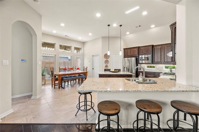 19718 Yellow Hibiscus Ln, Cypress, TX 77433 - kitchen featuring appliances with stainless steel finishes, a peninsula, dark brown cabinetry, a kitchen island, and a kitchen breakfast bar