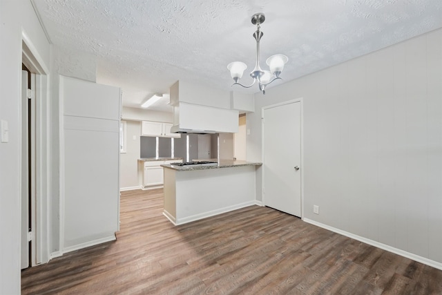10427 Envoy St, Houston, TX 77016 - kitchen with wood finished floors, white cabinets, a chandelier, a textured ceiling, and a peninsula
