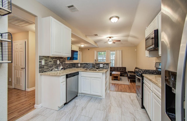 5409 Gold St, Houston, TX 77026 - kitchen with appliances with stainless steel finishes, a peninsula, a ceiling fan, and white cabinets