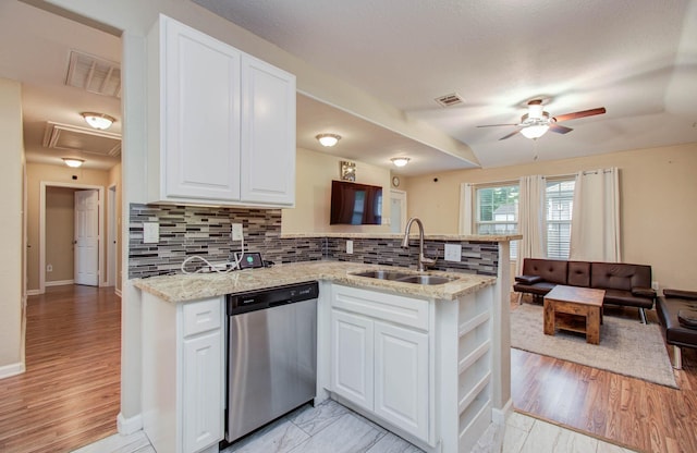 5409 Gold St, Houston, TX 77026 - kitchen with stainless steel dishwasher, a peninsula, a ceiling fan, white cabinets, and tasteful backsplash