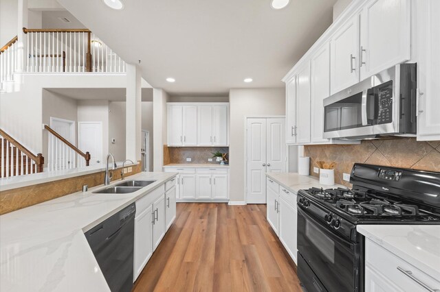 9415 Vista Falls Ct, Richmond, TX 77469 - kitchen with black appliances, tasteful backsplash, light wood finished floors, white cabinets, and light stone countertops