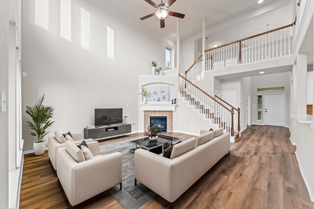 9415 Vista Falls Ct, Richmond, TX 77469 - living room featuring a ceiling fan, a high ceiling, wood finished floors, stairway, and a fireplace
