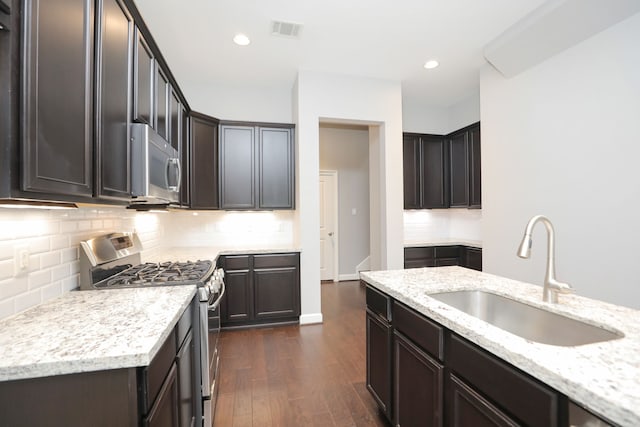 5120 Larkin St, Houston, TX 77007 - kitchen with stainless steel appliances, dark wood finished floors, light stone countertops, tasteful backsplash, and dark brown cabinets