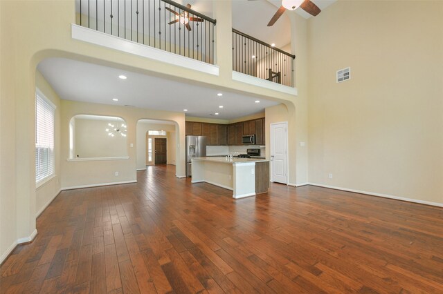 24030 Tirso River Ct, Katy, TX 77493 - unfurnished living room featuring arched walkways, ceiling fan, dark wood-type flooring, and a high ceiling