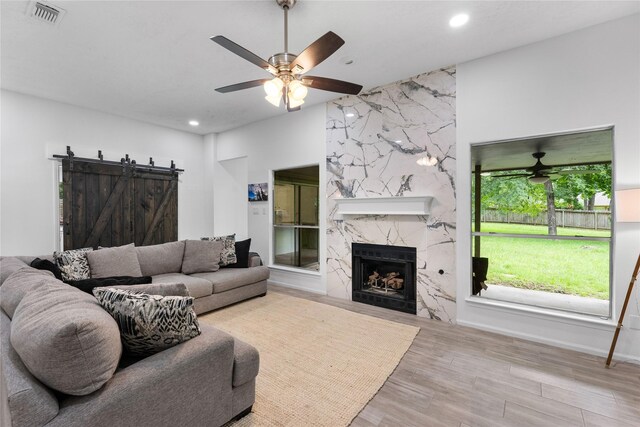 2403 Mustang Dr, Conroe, TX 77384 - living room with ceiling fan, wood finished floors, a barn door, recessed lighting, and a premium fireplace