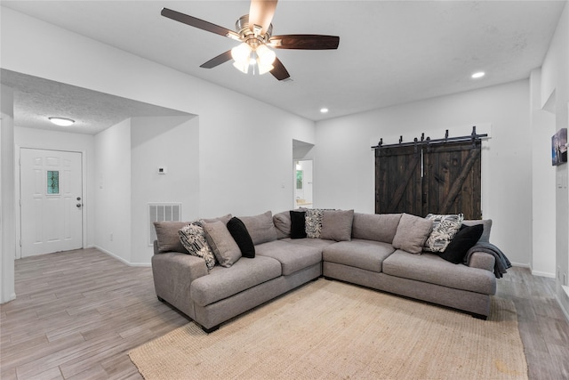 2403 Mustang Dr, Conroe, TX 77384 - living room with light wood-type flooring, a barn door, a ceiling fan, and recessed lighting