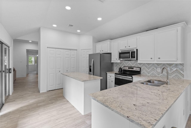 2403 Mustang Dr, Conroe, TX 77384 - kitchen featuring stainless steel appliances, a center island, vaulted ceiling, white cabinets, and backsplash