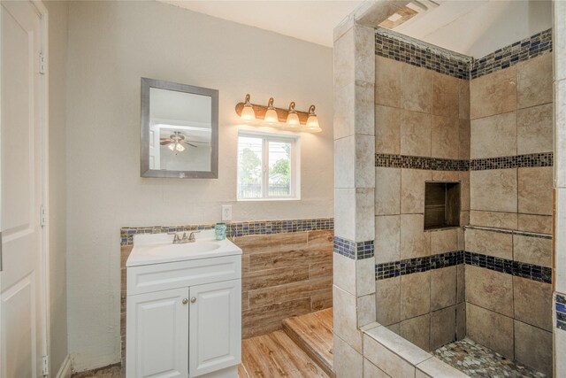 911 Wooding St, Houston, TX 77011 - bathroom with vanity, tiled shower, tile walls, a ceiling fan, and wood finished floors