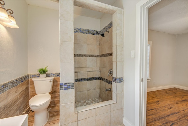 911 Wooding St, Houston, TX 77011 - bathroom with a tile shower, wood finished floors, and tile walls