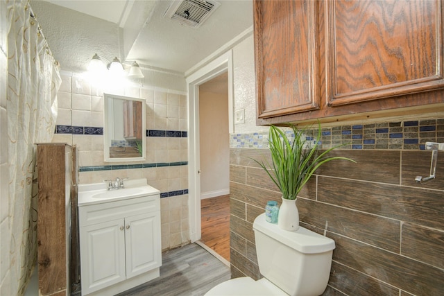 911 Wooding St, Houston, TX 77011 - bathroom with tile walls, wood finished floors, vanity, and tasteful backsplash