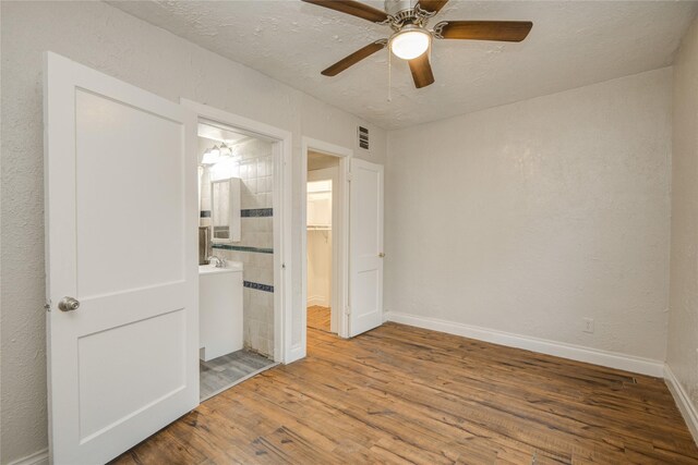 911 Wooding St, Houston, TX 77011 - unfurnished bedroom featuring wood finished floors, ensuite bath, and a ceiling fan