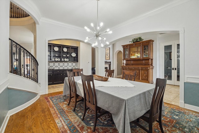 14002 Winding Springs Dr, Cypress, TX 77429 - dining space with arched walkways, light wood finished floors, a chandelier, crown molding, and stairs
