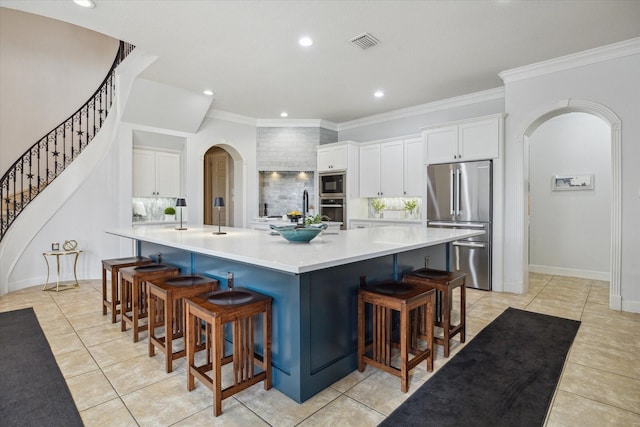14002 Winding Springs Dr, Cypress, TX 77429 - kitchen with arched walkways, stainless steel appliances, a breakfast bar, white cabinetry, and crown molding