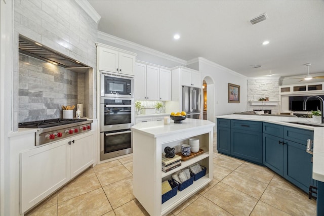 14002 Winding Springs Dr, Cypress, TX 77429 - kitchen with stainless steel appliances, open floor plan, arched walkways, blue cabinetry, and decorative backsplash