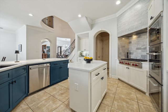 14002 Winding Springs Dr, Cypress, TX 77429 - kitchen featuring appliances with stainless steel finishes, arched walkways, crown molding, blue cabinets, and backsplash