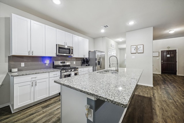 18827 Palmetto Hills Dr, New Caney, TX 77357 - kitchen featuring stainless steel appliances, dark wood finished floors, an island with sink, white cabinetry, and tasteful backsplash