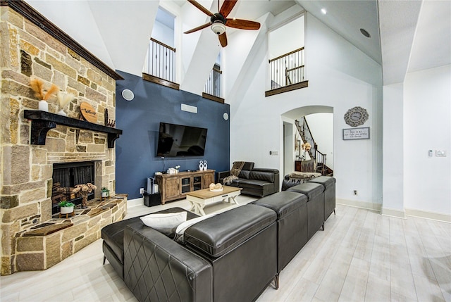 27818 Pinpoint Crossing Dr, Katy, TX 77494 - living area with a ceiling fan, stairs, arched walkways, a stone fireplace, and high vaulted ceiling