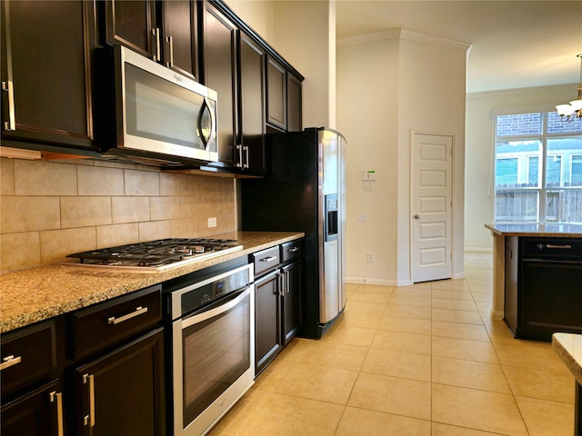 22106 Flashing Ridge Dr, Spring, TX 77389 - kitchen with appliances with stainless steel finishes, decorative backsplash, a chandelier, light stone countertops, and ornamental molding